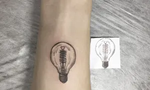 Nowy tatuaż żarówka na skórze, obok szkicu. Symbol pomysłu i światła.