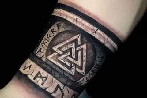 Imponujący tatuaż wikingów na przedramieniu, z symbolem Valhalli i runami, wygląda jak starożytny artefakt.